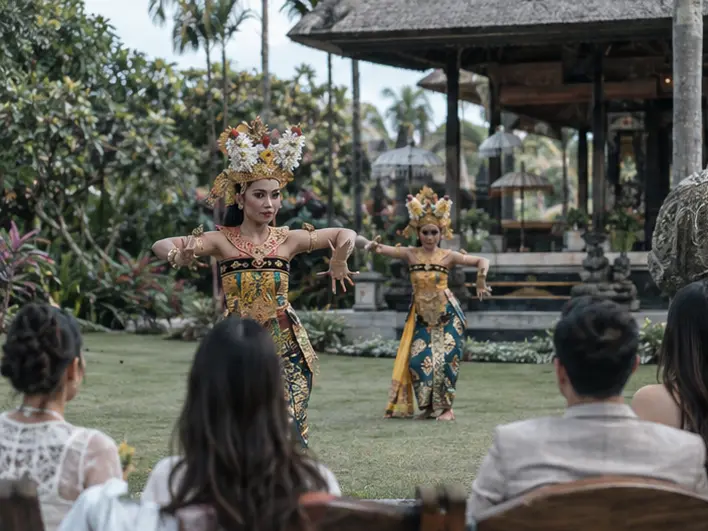 Traditional Balinese dancers performing near a garden pavilion for a small seated audience of event guests in destination event.