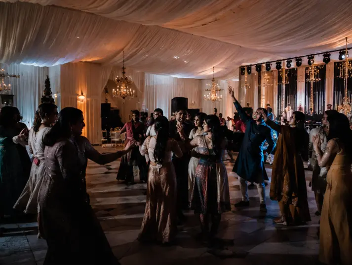 The Grand Plan EO Indian wedding celebration with guests dancing beneath elegant indoor lighting